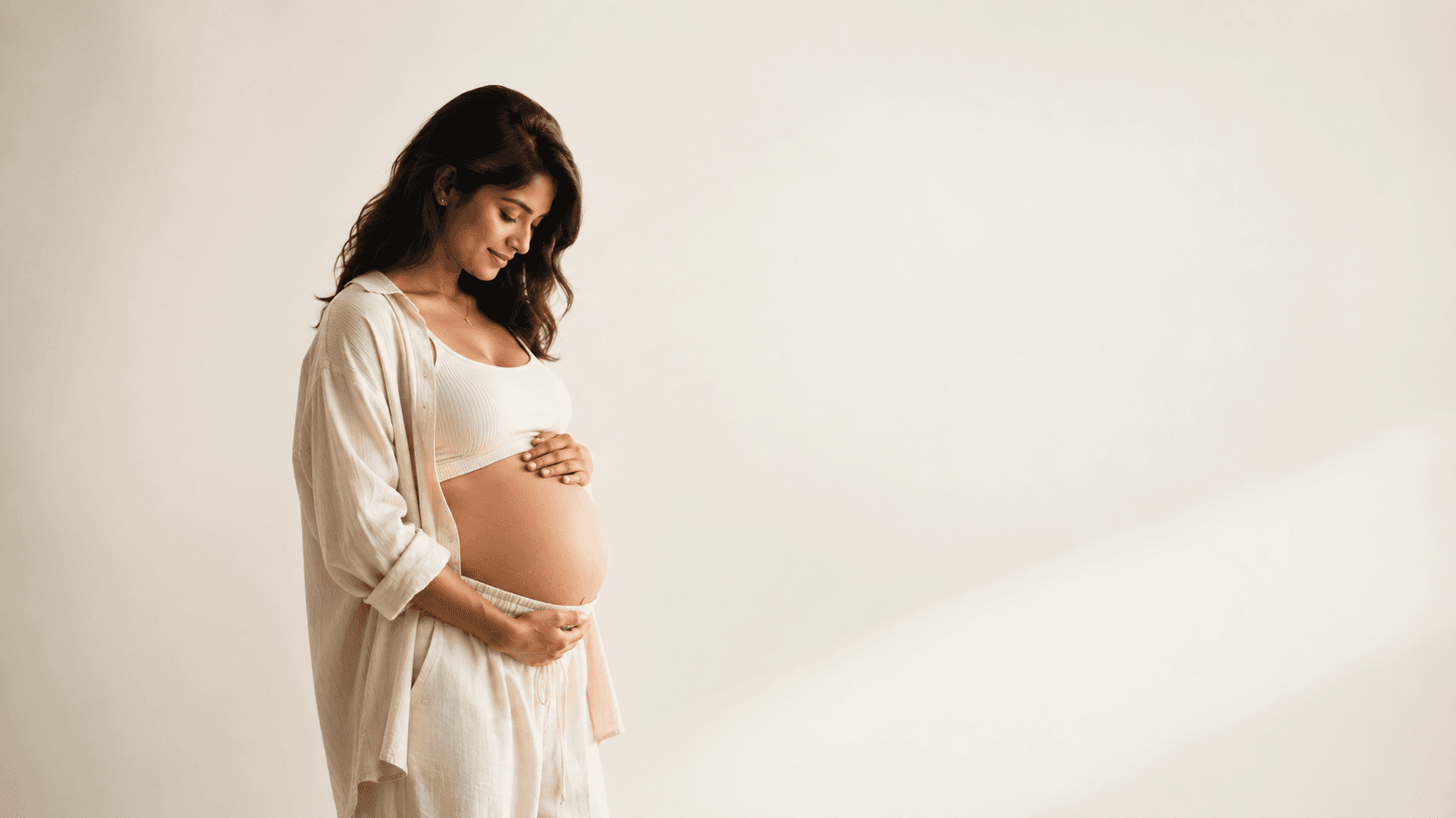 Expecting mother cradling her belly in soft natural light